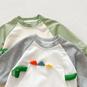 Detailopname van de schattige babyromper met 3D-dinosauruszak en handige drukknoppen.