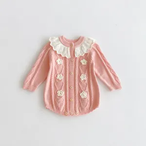 Baby girl knit romper detail, pink long-sleeve bodysuit with white ruffle collar and crochet flowers.