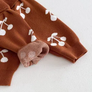 Detailed view of baby toddler brown knit cardigan featuring cute white cherry pattern fabric.