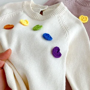 Detail pull en tricot pour bebe avec decorations florales au crochet colorees et texture douce