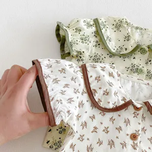 Cute floral baby doll collar top detail view, soft fabric and delicate wood buttons close up.
