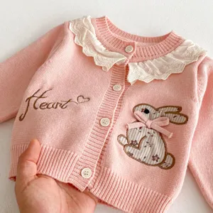 Detailopname van het roze gebreid vestje voor baby's met schattige konijnenborduursel en kantkraag.