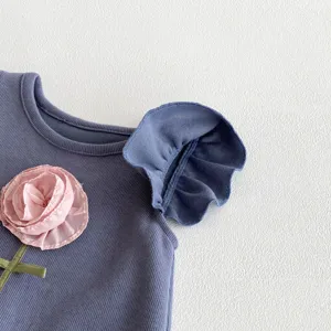 Vista detallada del body para bebé niña con aplicación de flor rosa y mangas con volantes bonitos.