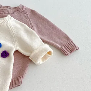 Vue détaillée du pull tricoté pour bébé, texture douce, jolis détails de fleurs au crochet.