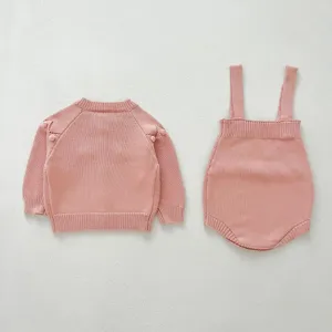 Detailed view of pink baby knitted sweater and strap bloomers set, soft texture, cozy infant wear.