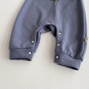Detalle de mono de bebé acanalado, pelele gris azulado con botones a presión, algodón suave.