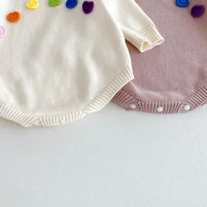 Combinaison tricotée pour bébé avec de jolies fleurs crochetées colorées et manches longues.