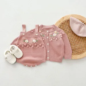 Detailed view of a cute baby pink knit cardigan and romper set with handmade floral embroidery.