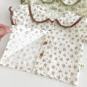 Close-up detail of baby floral shirt featuring contrast brown collar and wooden buttons.