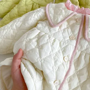 Detail shot showing the soft quilted texture, pink ruffles, and buttons of the baby winter coat.