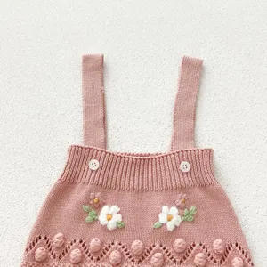 Pink knit baby romper detail, cute floral embroidery and bobble knit design with white buttons.
