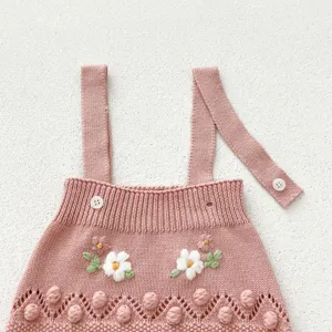 Baby knit romper detail, pink handmade flower embroidery, cute pom-pom knitwear newborn clothing.