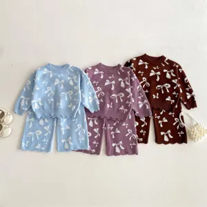 Detailed view of cute girls knit sweater and pants set featuring white bow jacquard pattern.