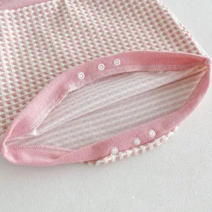 Detailed shot of infant baby plaid cardigan with pink snap buttons and soft ribbed trim.