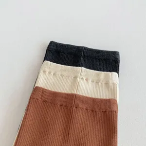 Primo piano dettagliato di leggings in maglia per neonati in tre colori con vita a costine.