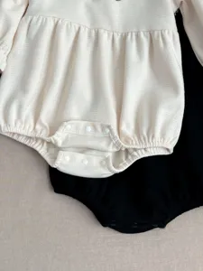 Infant baby waffle knit romper detail close-up, soft cotton bodysuit in neutral colors.