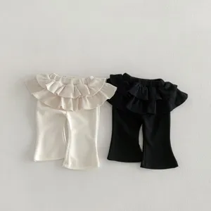 Close-up detail view of baby girls ruffle flared pants, featuring waist ruffles and cut.
