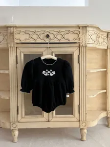 Detailed view of black infant baby romper featuring delicate white floral embroidery and lace trim.