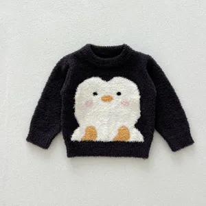 Gros plan détaillé d'un pull pour enfants doux et duveteux avec un joli motif de pingouin.