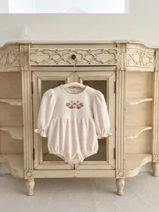 Detailed view of baby girl long sleeve romper with cute floral print and delicate ruffles.