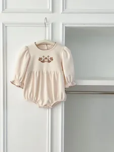 Detailed view of baby girl knit romper with brown floral embroidery and cute lace trim.
