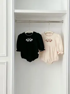 Detailed view of cute baby girl long sleeve romper with floral embroidery and lace collar.