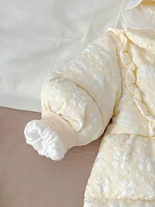 Infant winter down jumpsuit detail, floral embossed baby snowsuit with soft ruffle hood trim.