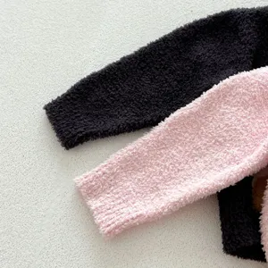 Détail de manches de vêtement d'intérieur en peluche douce, noir et rose, texture chaude.