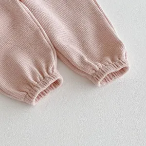 Dettaglio polsino pantaloni tuta neonato in maglia waffle rosa, abbigliamento per bambini.