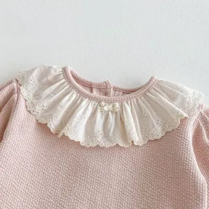 Primo piano dettagliato di una felpa rosa per bambini con colletto in pizzo bianco e fiocco.