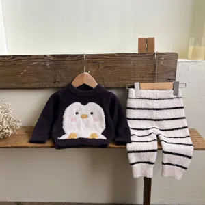 Détail de tenue d'intérieur bébé confortable avec pull pingouin mignon et pantalon rayé.