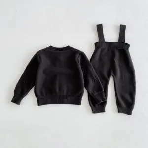 Schwarzes Strick-Babypullover- und Latzhosen-Set Detail, weicher Stoff, schöne Ärmelstickerei.