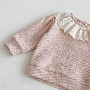 Primo piano dettagliato della felpa rosa waffle per bambini con elegante colletto in pizzo.