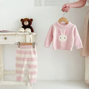 Vue détaillée d'un pull bébé rose duveteux avec motif de lapin et pantalon rayé.