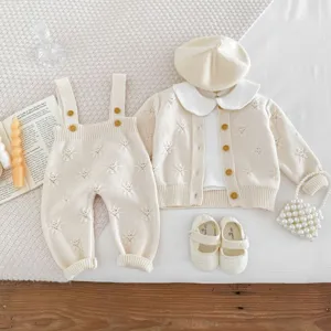 Detailansicht des Baby Strickjacken und Latzhosen Sets in Creme mit zarten Blumenmustern.