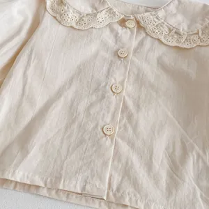 Primo piano dettaglio della camicia di cotone da bambina con colletto in pizzo e bottoni.
