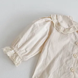 Dettaglio della camicia in cotone beige da bambina con colletto in pizzo e maniche a palloncino.
