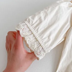 Primo piano della manica della camicetta in cotone bianco da bambina con delicato bordo in pizzo.