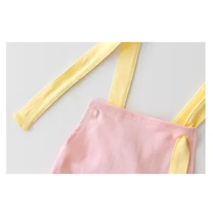 Süßes Baby Strampler Detail, rosa Jumpsuit mit gelben Trägern, weiche Kleidung.
