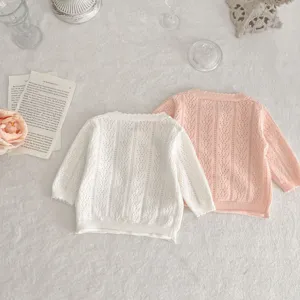 Primo piano dettagliato di cardigan per neonati in morbido cotone bianco e rosa con graziosa trama.