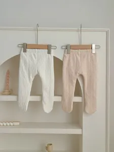 Baby knit tights detail view, soft cotton material, cute infant clothing display on arch shelf.