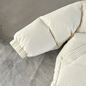 Primer plano de la manga de un abrigo de plumón para bebé blanco, detalle de invierno.