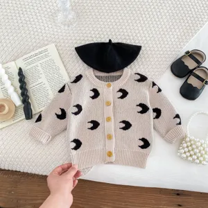 Detailed view of baby knitted cardigan with moon print, flat lay style with accessories.
