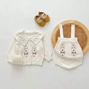 Gros plan détaillé du joli ensemble gilet et barboteuse en tricot bébé avec broderie florale.