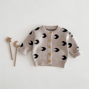 Detailed view of baby knit cardigan with crescent moon pattern and wood buttons closeup shot.