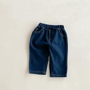 Dettaglio pantaloni denim morbidi bambino blu scuro, vita elastica, tasche anteriori, tessuto.