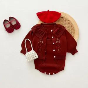 Vue détaillée de l'ensemble gilet tricoté bébé, fleurs brodées et accessoires rouges.
