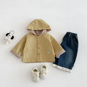 Detailed view of baby hooded windbreaker jacket with plaid lining, denim pants and sneakers.