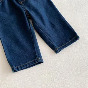 Dettaglio ravvicinato di pantaloni in morbido denim blu scuro per bambini con cuciture gialle.