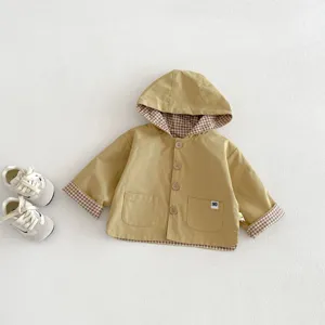 Detailed view of the kids reversible hooded trench coat in khaki with plaid lining.